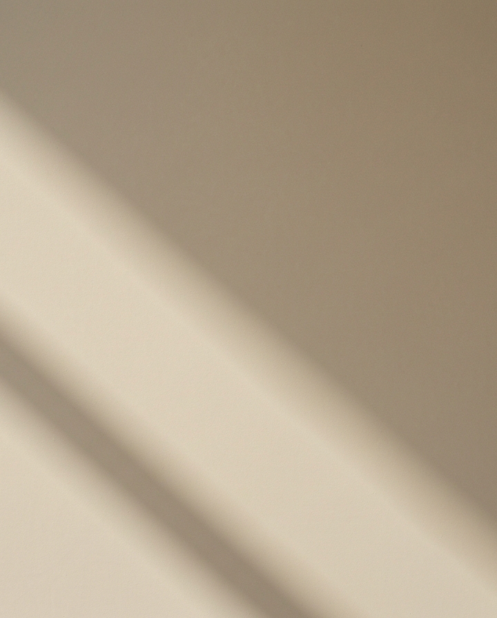 Zbliżenie na gładką, beżową ścianę z naturalnym oświetleniem i subtelnymi cieniami