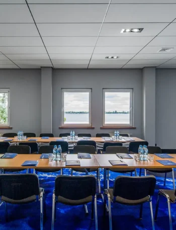 Sala konferencyjna w Hotelu 500 Zegrze z ustawieniem stołów w podkowę, projektorem i widokiem na Jezioro Zegrzyńskie.