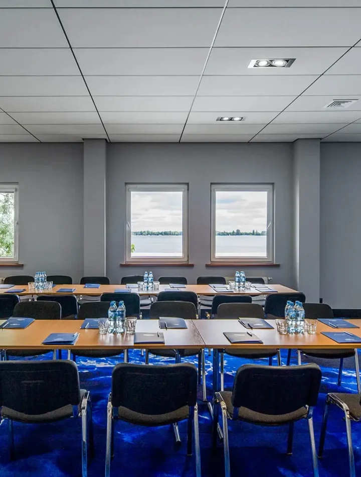 Sala konferencyjna w Hotelu 500 Zegrze z ustawieniem stołów w podkowę, projektorem i widokiem na Jezioro Zegrzyńskie.